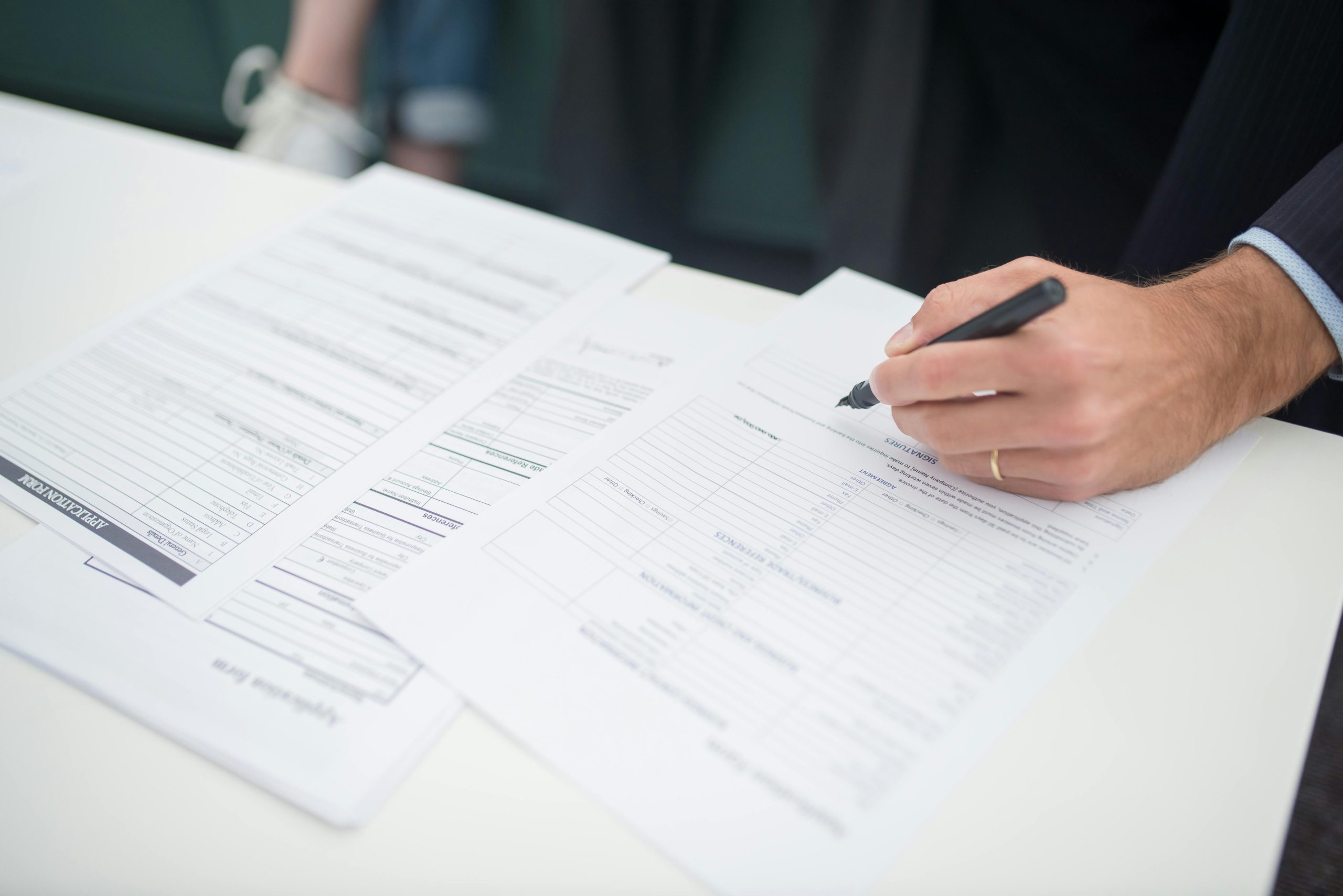 pexels-photo-8441817-8441817 Close-up of a hand signing insurance documents in an office setting.